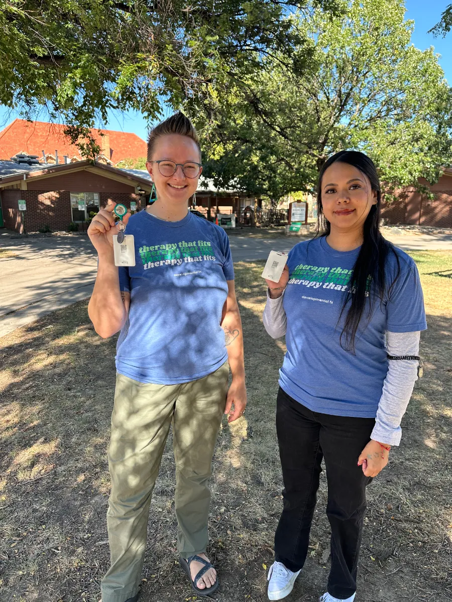 Two Developmental FX therapists holding up their Sense Tag lone worker badges outside the clinic